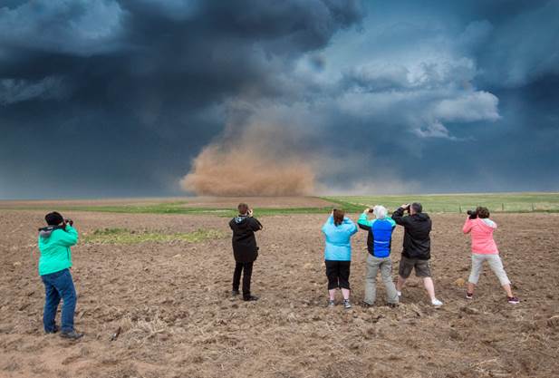 Fotografía de un grupo de personas que toman fotografías de una poderosa tormenta que se acerca, para el artículo Beneficios de huracanes.
