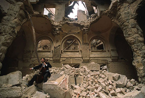 Esta fotografía de un cellista sentado entre escombros y tocando su instrumento ilustra el tema Haciendo música en medio de escombros, en editoriallapaz.org.