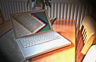 An open Bible on the screen of a laptop  resting on a desk illustrates the Shappley Report for December, 2014.