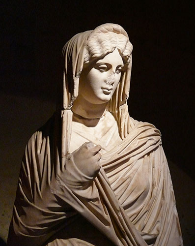 La mujer griega de esta escultra tiene el velo sobre la cabeza y su mano derech está en la posición que exigía la modestia, de acuerdo las normas establecidas en Grecia y el Imperio Romano del siglo I.
