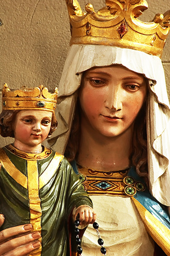 En esta fotografía, el niñito Jesús aparece con un rosario en la mano izquierda, juntamente con María, ambos con coronas de oro y gemas, ambos con vestimentas de realeza, ilustración para el tema: ¿Fue católico en Señor Jesucristo?