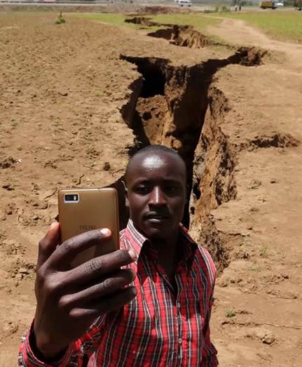 Un hombre en África se toma una selfie frente a una grieta larga, profunda y en zigzag, formada por el movimiento de las placas tectónicas.