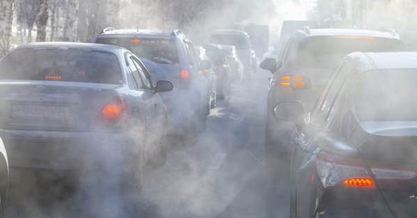 Fotografía de filas de vehículos que emiten tantos gases tóxicos que se ven rodeados de nubecillos grisáceos.