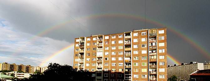 Fotografía de un arco iris dobles detrás de un edificio grande de apartamentos.