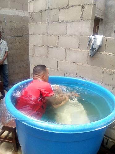 Fotografía de un bautismo por inmersión en una gran bañera llena de agua.
