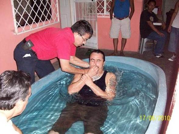 Fotografía del bautismo por inmersión de un varón en una gran bañera llena de agua.