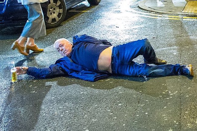 Fotografía del parrandero, “el hombre azul”, barrigón de 47 años de edad, acostado en la calle durante unos veinte minutos, tan ebrio que no se acuerda de nada. Luego se levanta y se va a su casa. Eso de las fotografías tomadas de él aquella noche no le incomoda en nada.