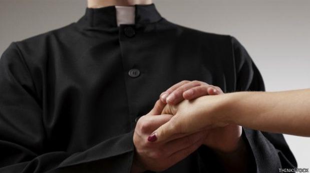 Esta fotografía de un cura católico romano que sostiene entre sus dos manos la mano de una dama ilustra el tema Católicos romanos hacen defensa, en editoriallapaz.org.