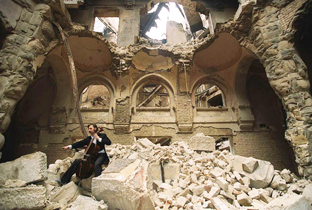 This photograph of a solitary musician playing his cello en the midst of ruins illustrates the subject Making Beautiful Music in the Midst of ruins, in editoriallapaz.org.