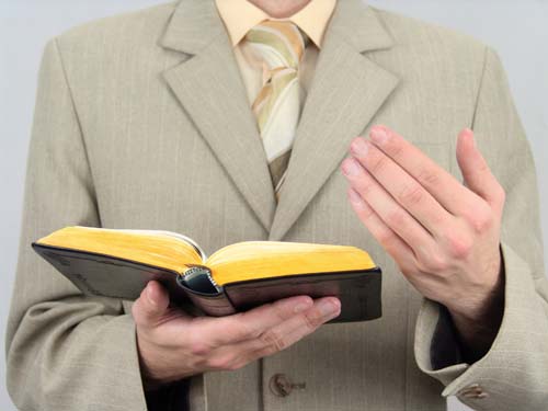 Esta fotografía de un predicador que sostiene la Biblia abierta en sus manos ilustra el ensayo Predicar doctrina, ¡NO! Solo el corazón del evangelio, en editoriallapaz.org.