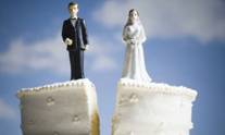 Imagen de una pareja de cerámica parada en en un pastel de boda partido por el medio, parado el novio en un lado y la novia en la otra mitad.