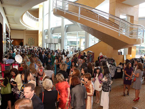 Fotografía de una multitud de personas en un centro comercial moderno donde se ven una escalera caracol, balcones y las fachadas de distintas tiendas.